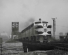 A black and white photo of a train exiting a bridge