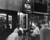 A black and white photo of passengers waiting to give their ticket to get on the train