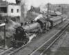 A black and white photo of a train approaching a station
