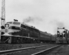A black and white photo of two trains traveling side by side