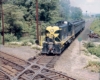 A green and yellow train approaching an intersection