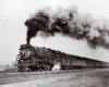 A black and white photo of a train with big black smoke coming out of its chimney