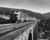 A black and white photo of a train crossing a bridge