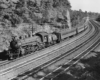 A black and white photo of a train with the conductor out the window