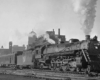 a steam engine and passenger cars departing Grand Central Station and Chicago in the background