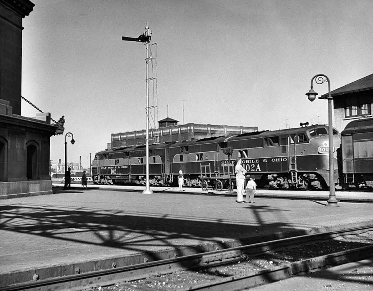 a diesel with passenger cars sitting in a station