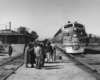 a group of passengers waiting to board a diesel passenger train