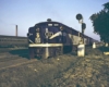 A blue and yellow train sitting in a grassy area next to a stop light