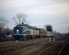 A blue and white train passing by a water tower