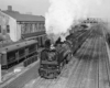 A train pulling into a station with big white smoke coming out of its chimney