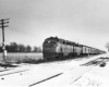 a diesel pulling passenger cars past a snowy field