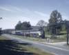 a diesel pulling passenger cars alongside a road