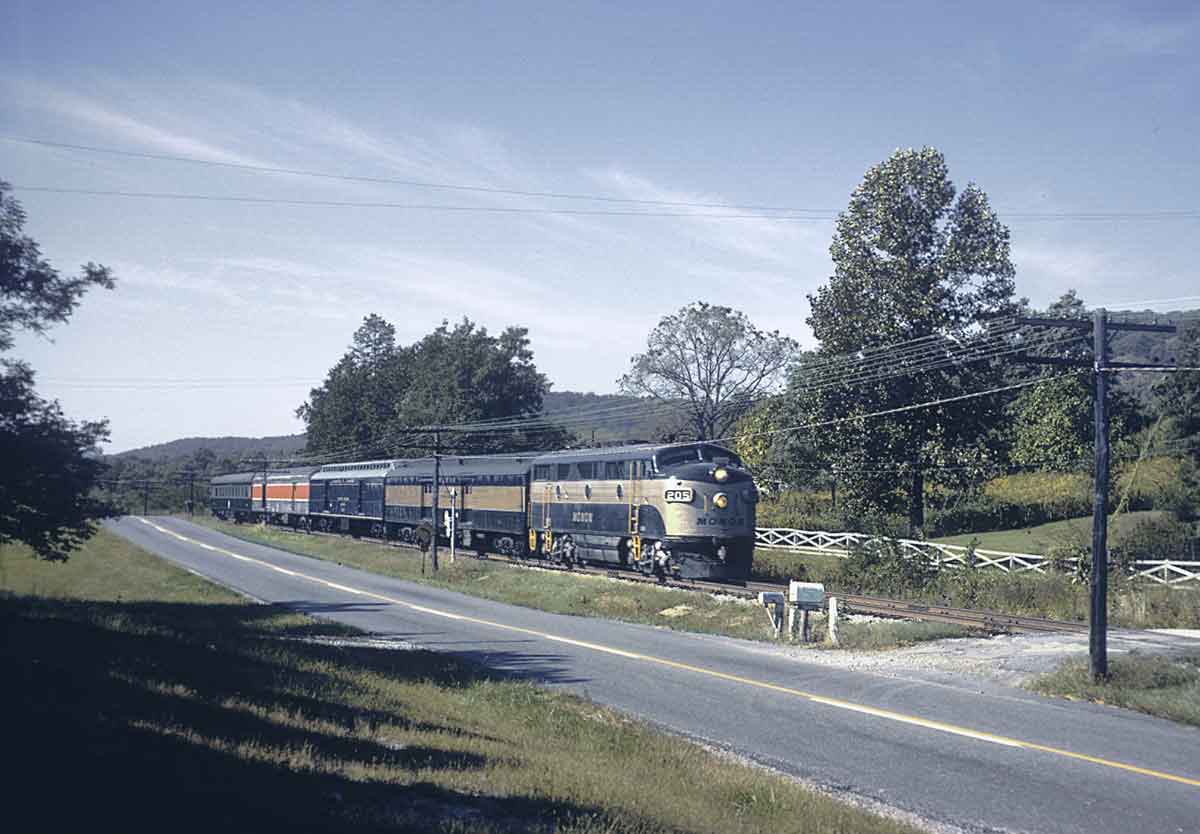 a diesel pulling passenger cars alongside a road