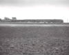 A distant black and white photo of a train passing by