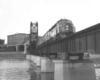 A black and white photo of a train travelling over a bridge