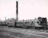 A black and white picture of a train parked outside a station