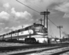 A black and white photo of an E7 locomotive stopped at an intersection on the tracks