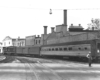 a diesel passenger train by some buildings