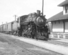 a stream engine passenger train by a building