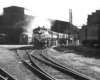 A diesel passenger train with a station in the background