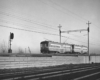 a black and white photo of a passenger car coming off a bridge