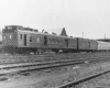 Motor car with two passenger cars in yard