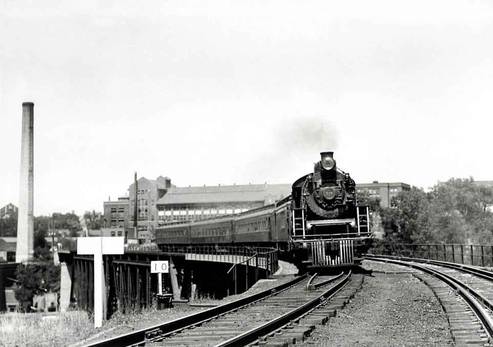 Steam locomotive with passenger train on curve on bridge