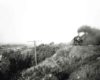 Steam locomotive on hillside with passenger train