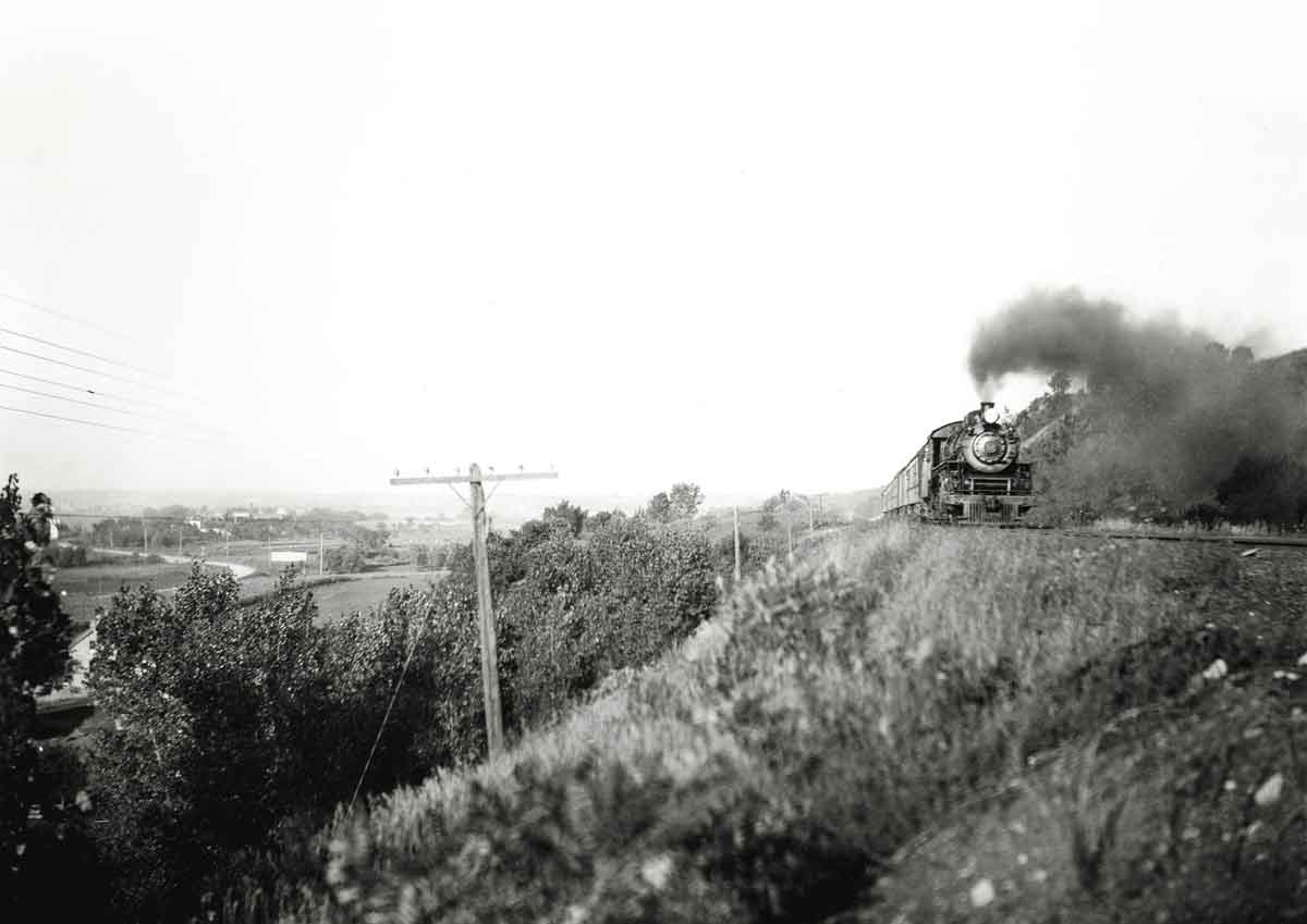 Steam locomotive on hillside with passenger train