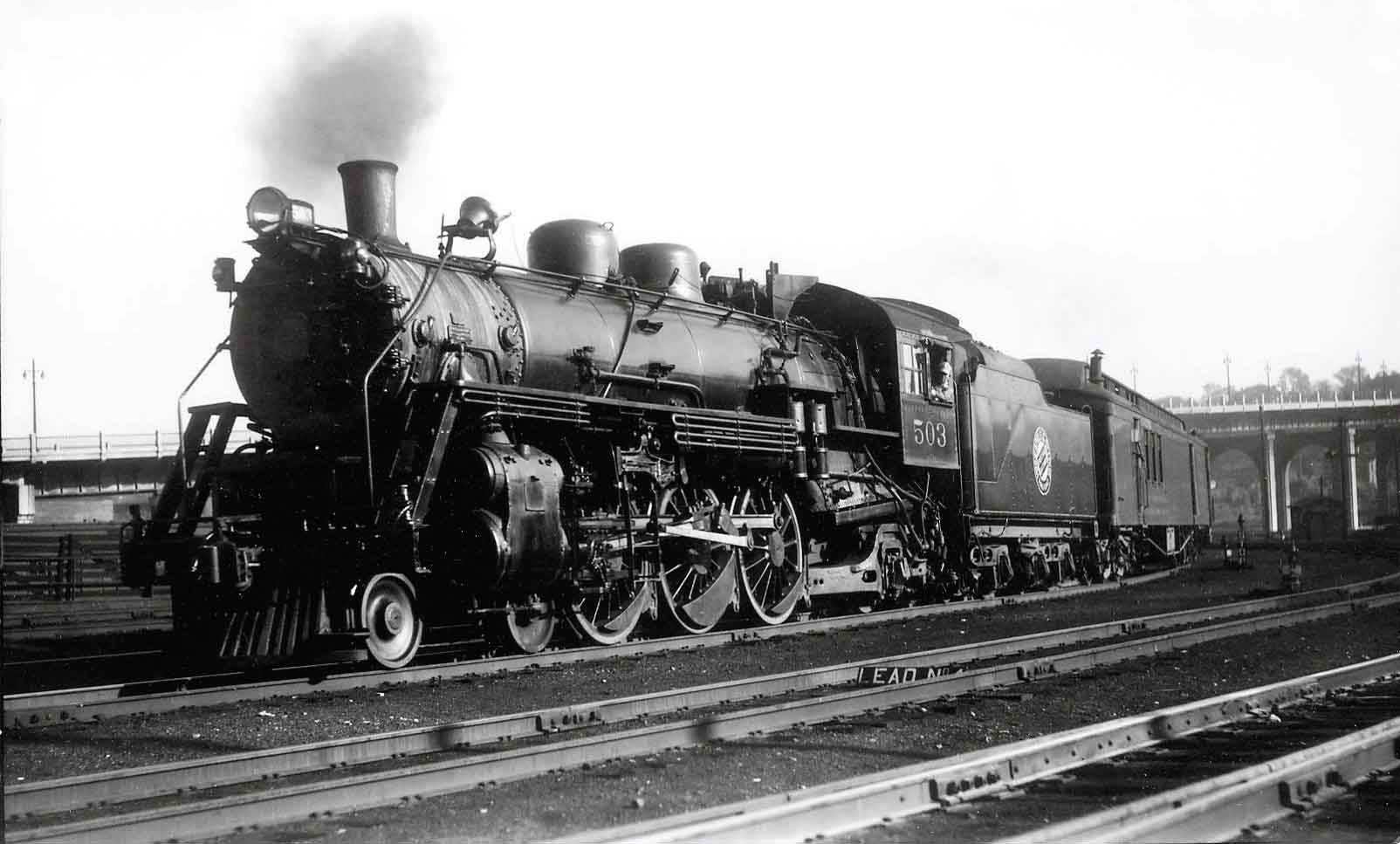 Steam locomotive with passenger train on curve under bridge