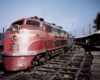 A red and orange train parked outside a station