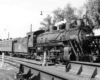 A black and white photo of a train parked at a station