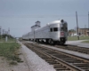 A silver train passing through a small town