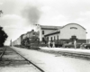 A black and white photo of a train passing by a Liberal building