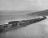 A passenger train on a narrow track surrounded by water