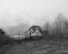 A black and white photo of a passenger train on a gloomy day
