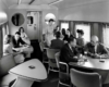 People sitting at tables, inside a train, talking
