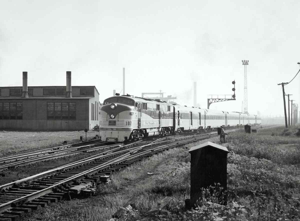 A train passing by a building and a stop light