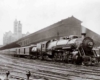 A black and white photo of a train leaving a station