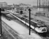 A black and white photo of a train parked outside a station