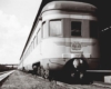 A black and white close up picture of a train parked outside a station