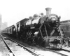 A black and white photo of a train leaving a station