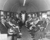 Men in suites sit in observation car