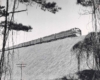 Two diesel locomotives with passenger train on high fill