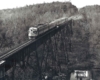 Two diesel locomotives and three passenger cars on high steel bridge