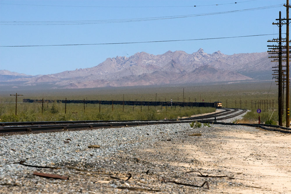 Big boy captured from a distance, turning a cover, with mountains in the background