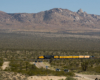 A distant shot of big boy passing by with mountains in the background