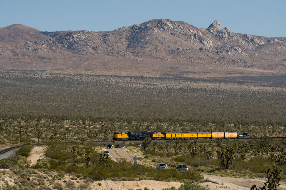 A distant shot of big boy passing by with mountains in the background