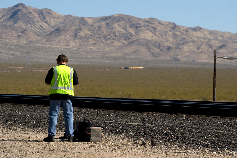 A worker standing next to the tracks as big boy approaches in the distance