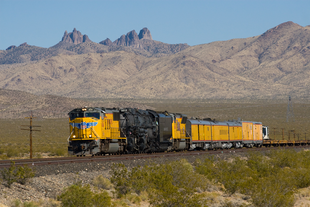 Big boy coming down the tracks with mountains in the background